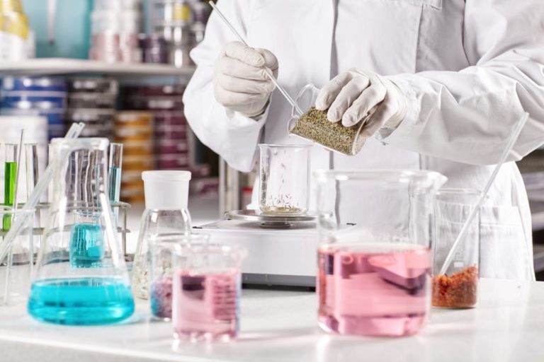 person in white gown mixing chemicals inside the laboratory