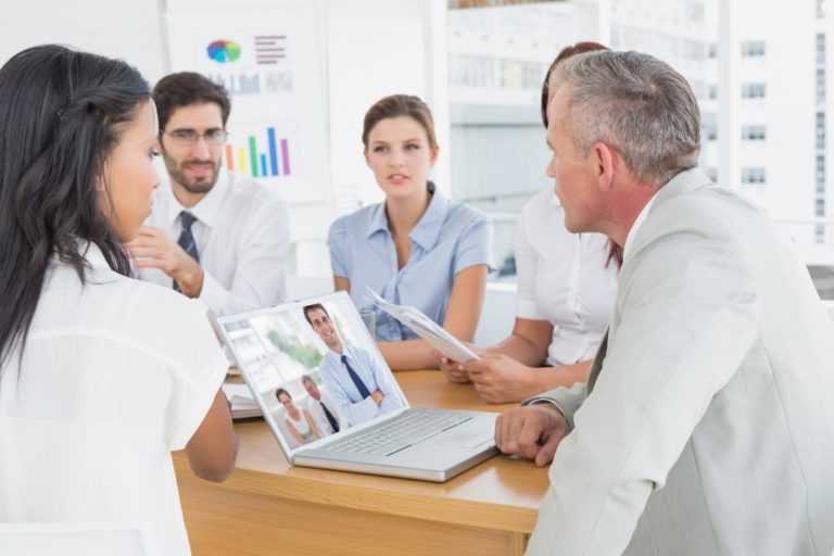 Cheerful businessman posing while his colleagues are working against business team discussing work details