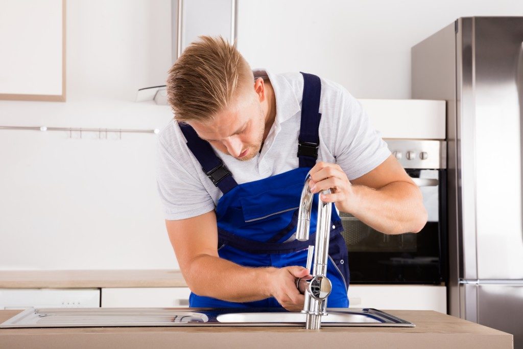 plumber fixing the faucet in the kitchen