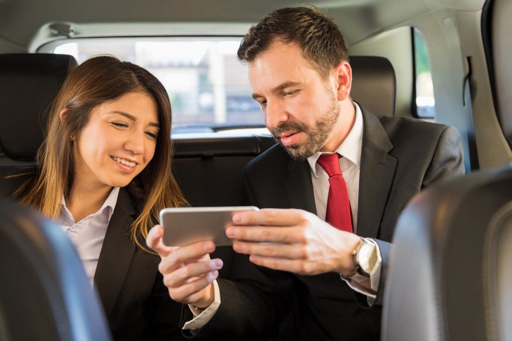 two young businesspeople riding in the backseat of a car