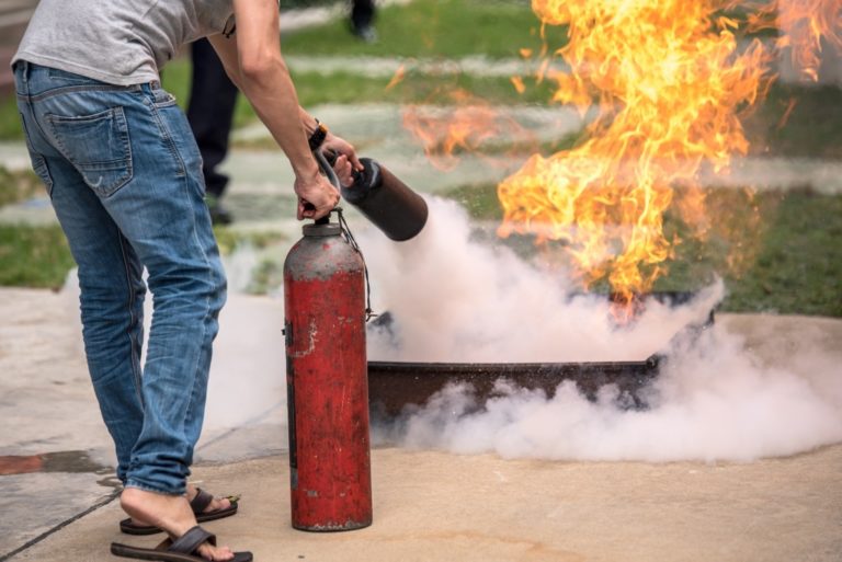 man putting out fire with a fire extinguisher