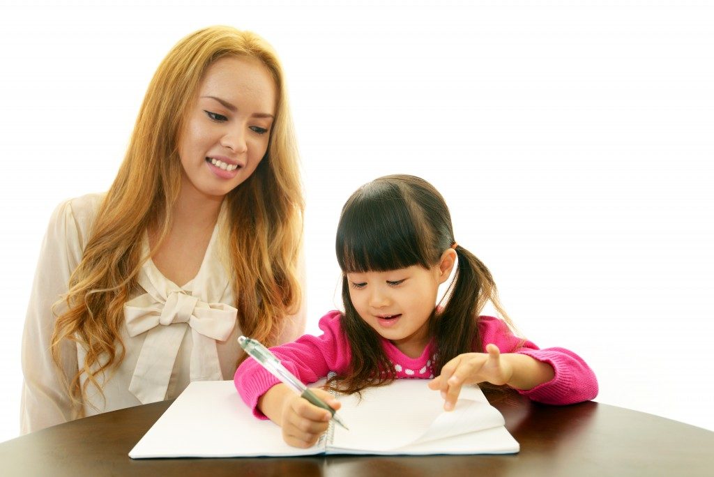 woman teaching little girl a different language