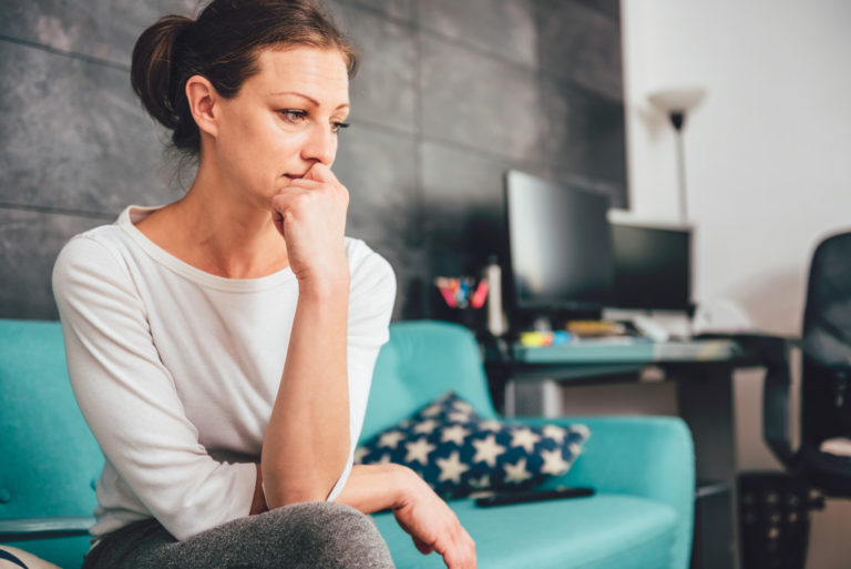 woman looking worried sitting on the couch